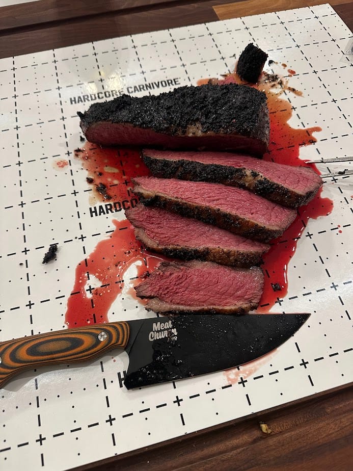 Beautifully charred Picanha sliced on a cutting board with a meat church Montana knife company blade.