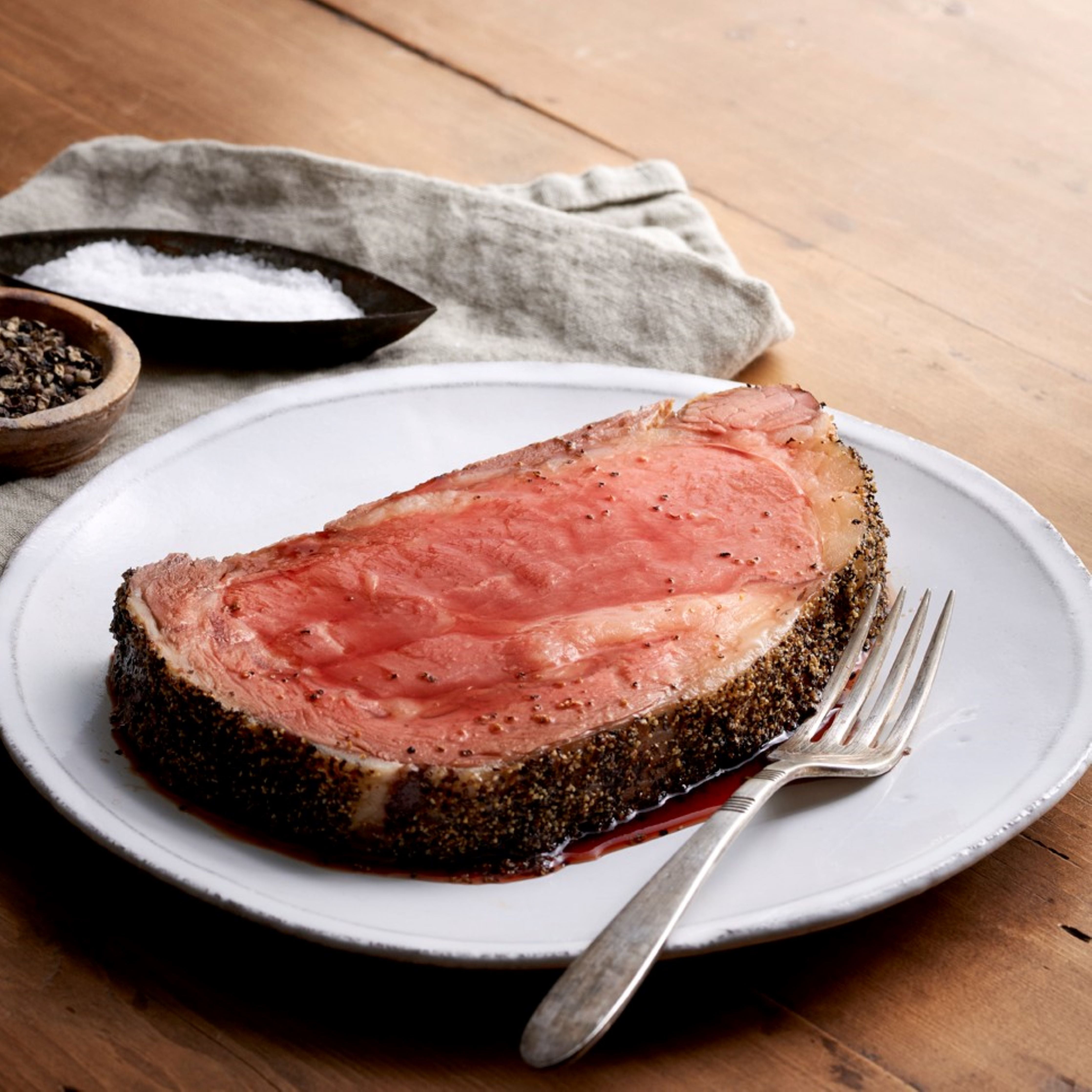 cut piece of tender pre cooked smoked prime rib on plate with fork and seasoning